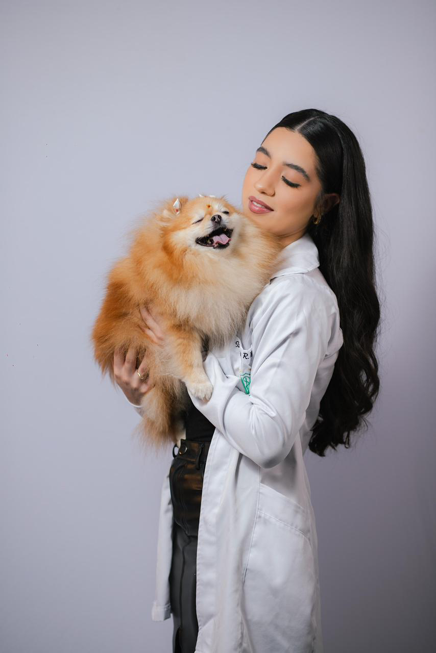 Izadora com jaleco abraçando Spitz Alemão